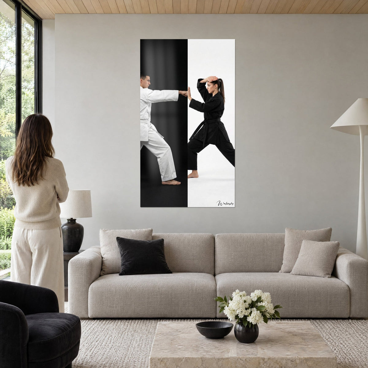 Quadro karateka in kimono bianco che colpisce la rivale in nero, sfondo diviso in bianco e nero, sopra un divano in un soggiorno luminoso