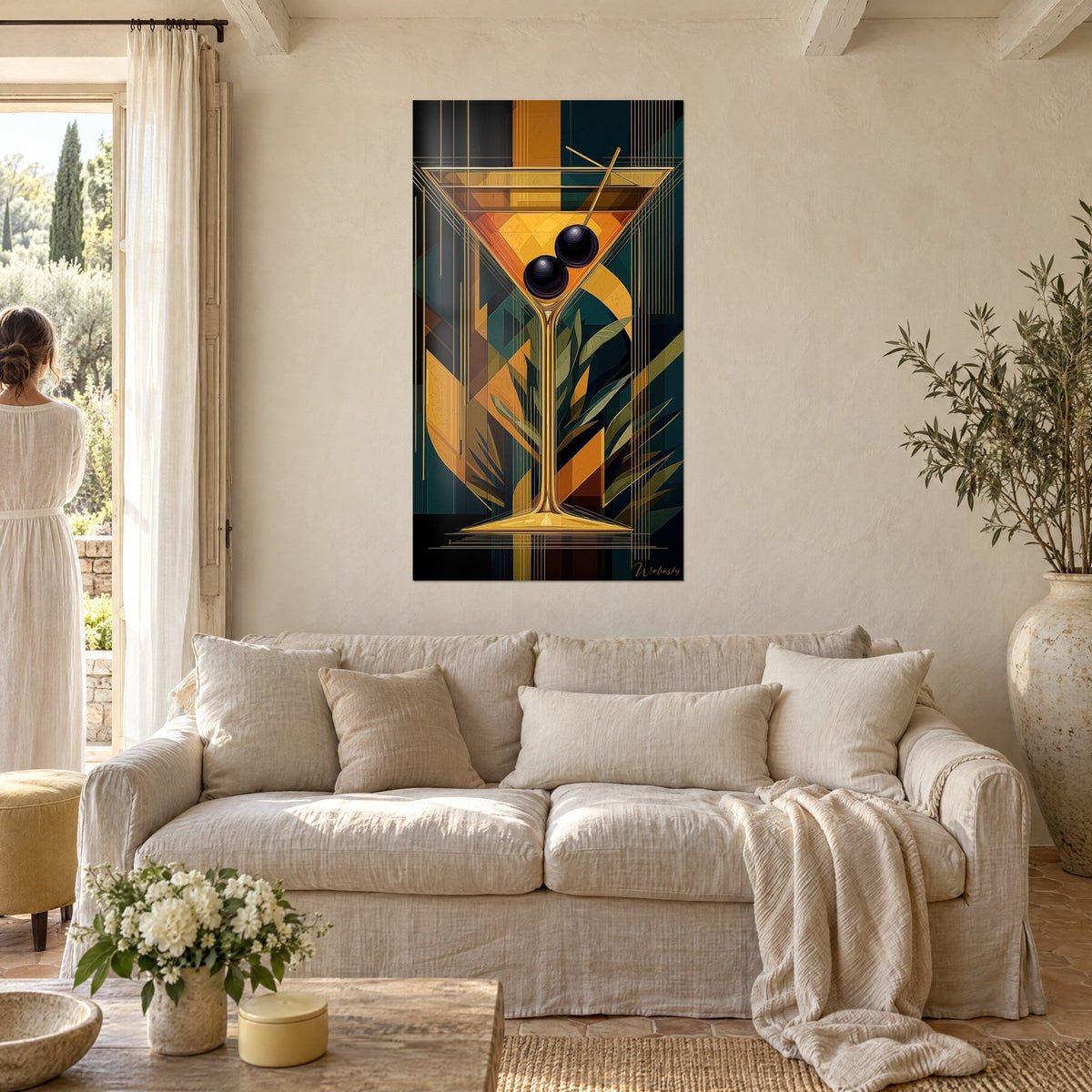 Schilderij gouden martini met twee zwarte olijven, achtergrond in dennengroen en oker, vrouw van achteren, boven een bank in een lichte woonkamer
