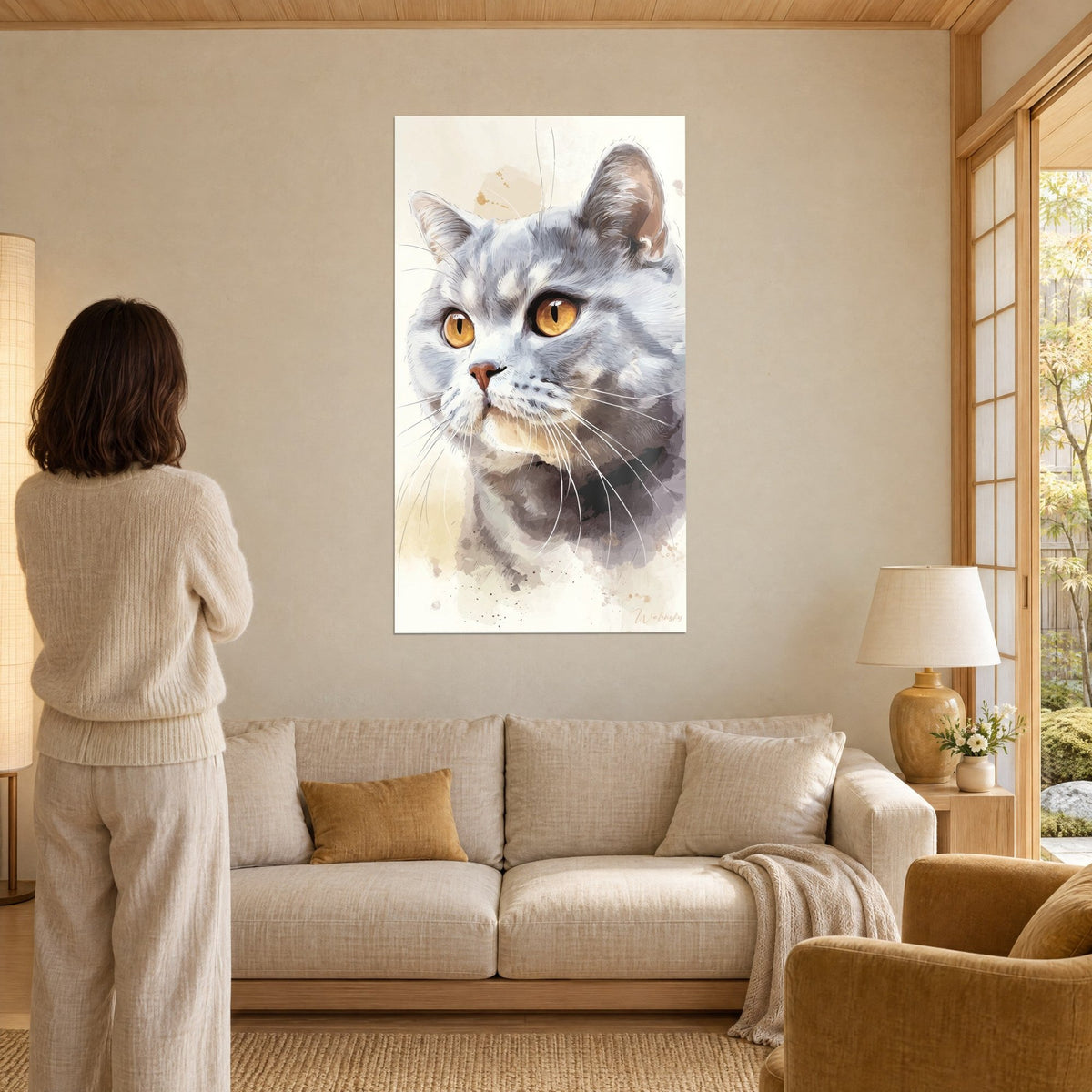 Tableau portrait de chat gris perle aux yeux ambre, moustaches blanches, visiteuse de dos, au-dessus d'un canapé dans un salon lumineux