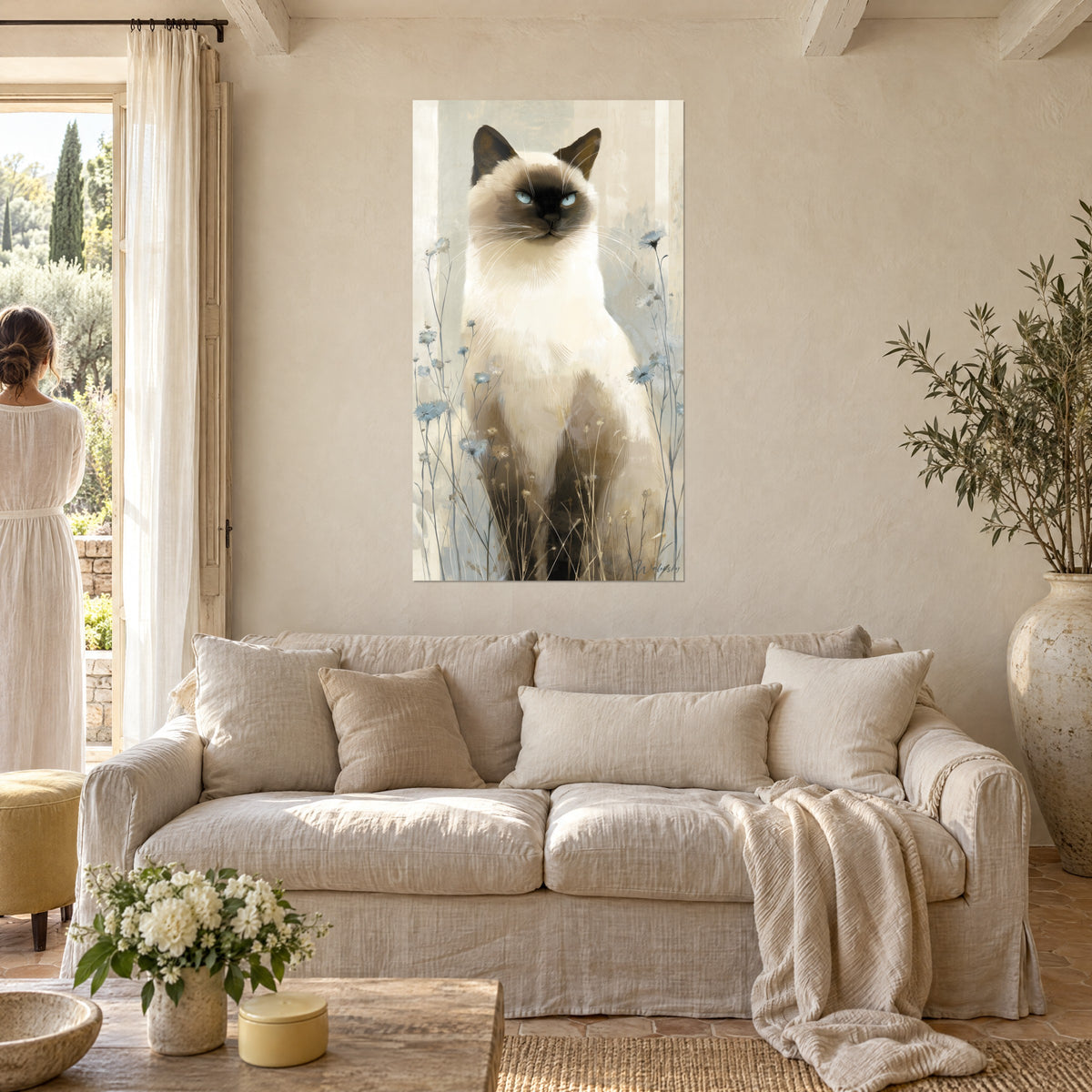 Quadro gatto siamese dagli occhi azzurri, pelo crema e maschera bruna, tra fiordalisi, sopra un divano in un soggiorno luminoso