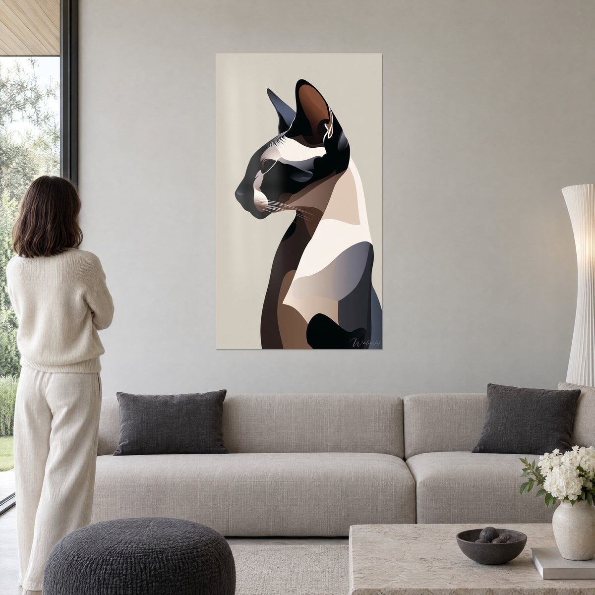 Tableau chat sphynx de profil en aplats noir et crème, oreille brune, femme de dos, au-dessus d'un canapé dans un salon lumineux