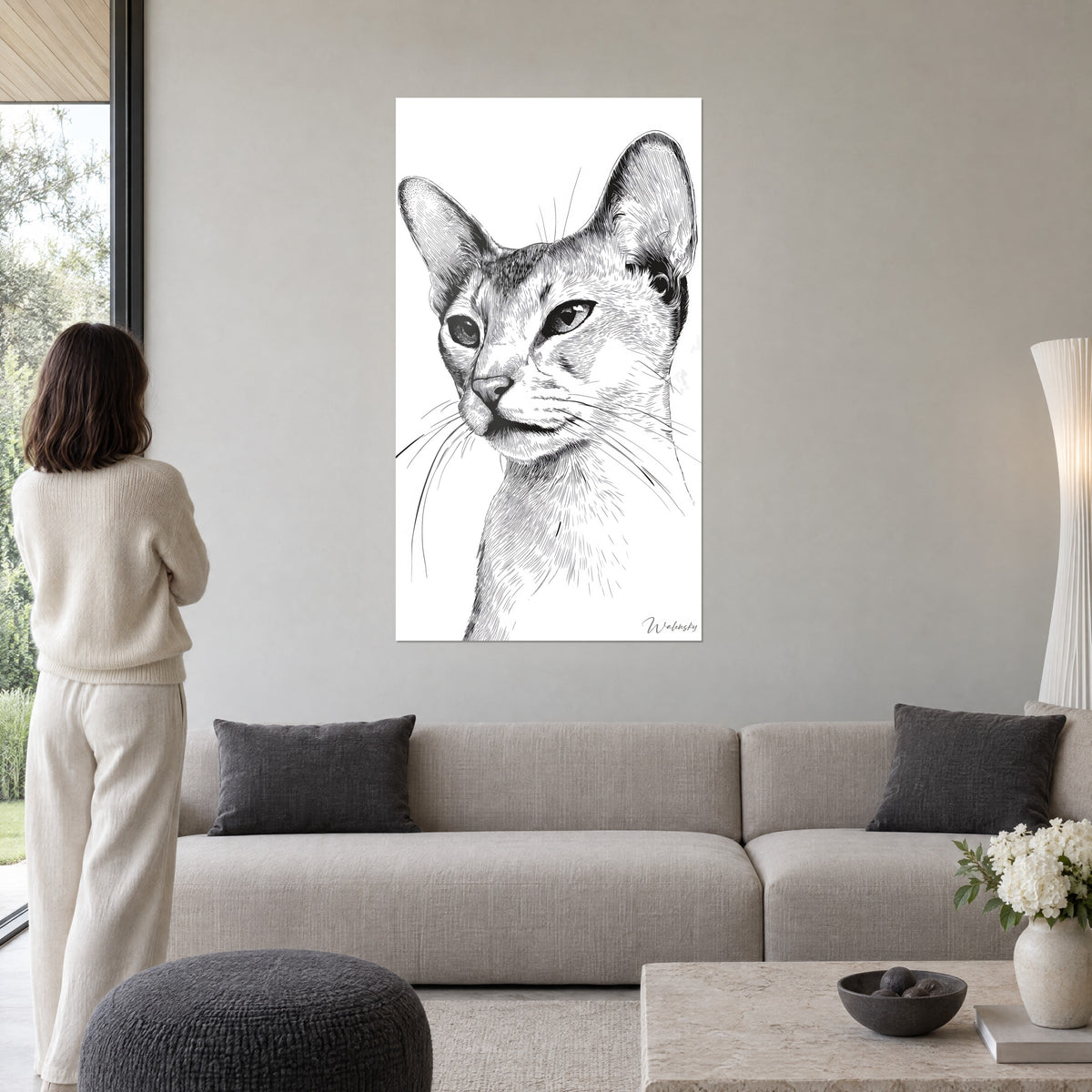 Cuadro retrato felino de grandes orejas, tinta negra sobre fondo blanco, encima de un sofá en un salón luminoso