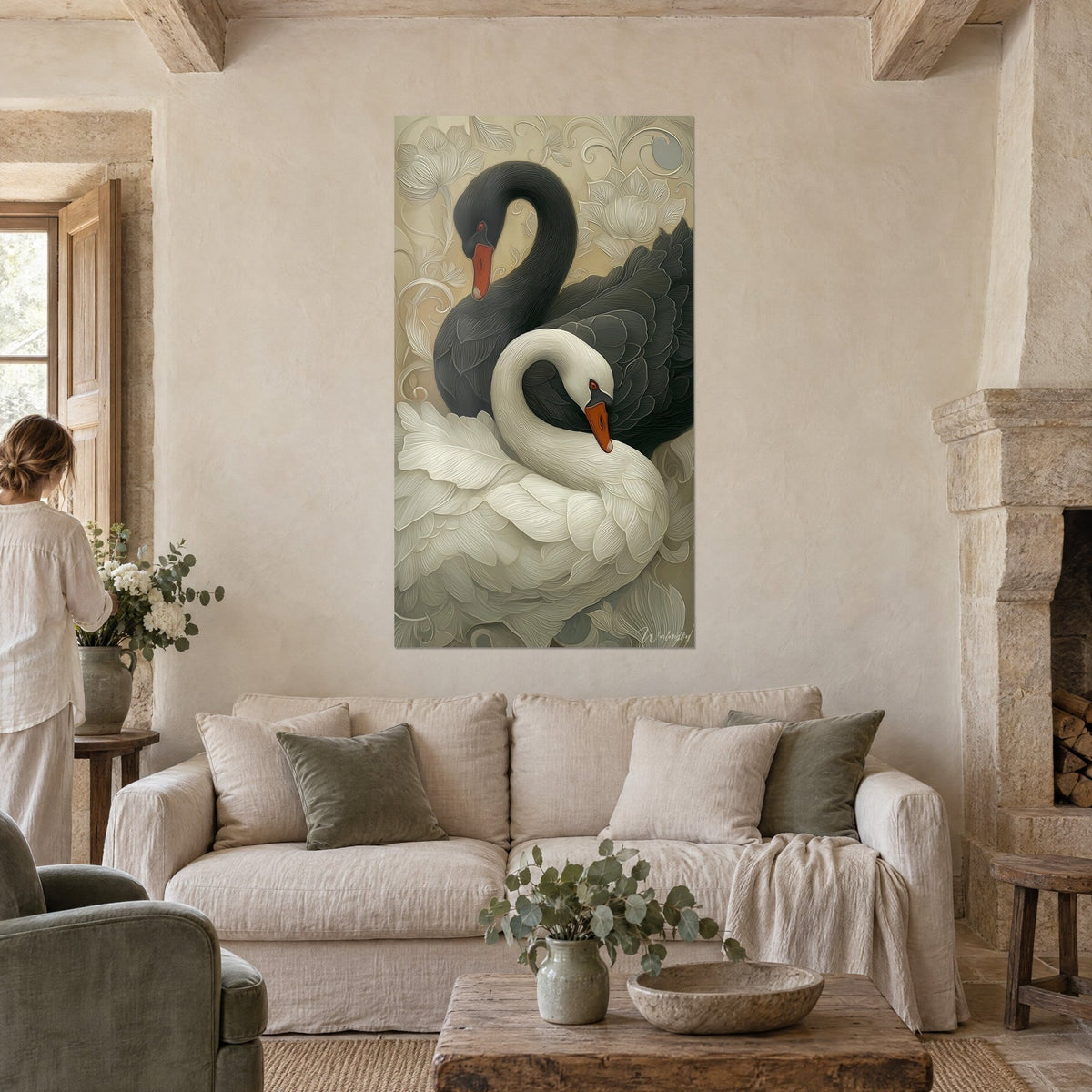 Tableau duo de cygnes noir et blanc aux plumes sculptées, motifs floraux beige, une femme de dos, au-dessus d'un canapé dans un salon lumineux