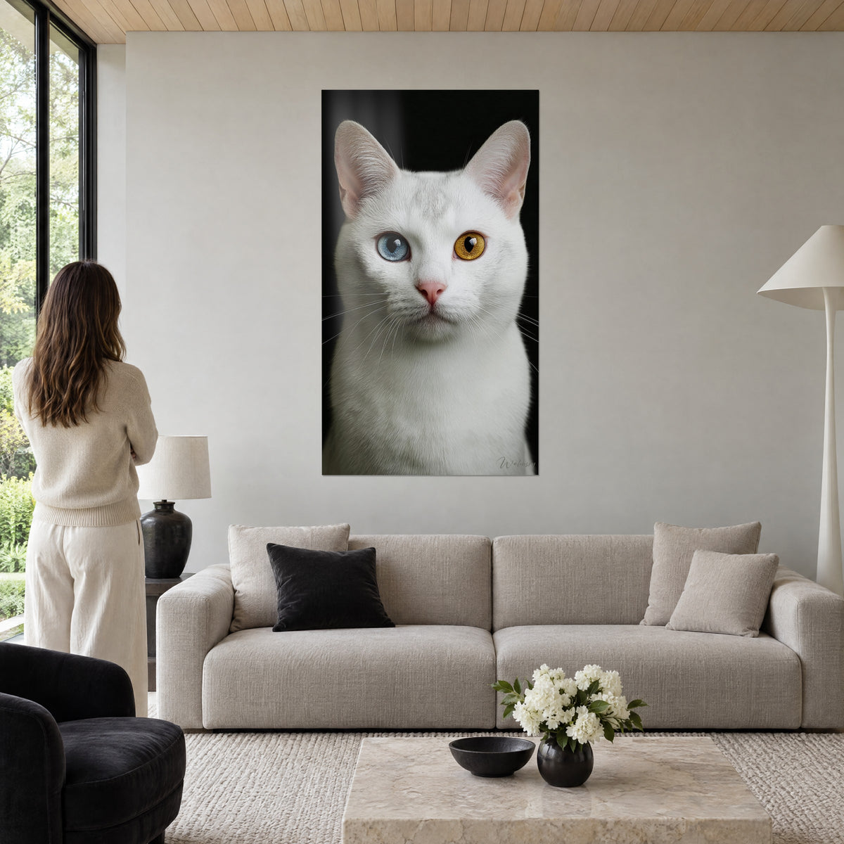 Gemälde weiße Katze mit verschiedenfarbigen Augen, eines blau, eines bernsteinfarben, schwarzer Hintergrund, Frau von hinten, über einem Sofa in einem hellen Wohnzimmer
