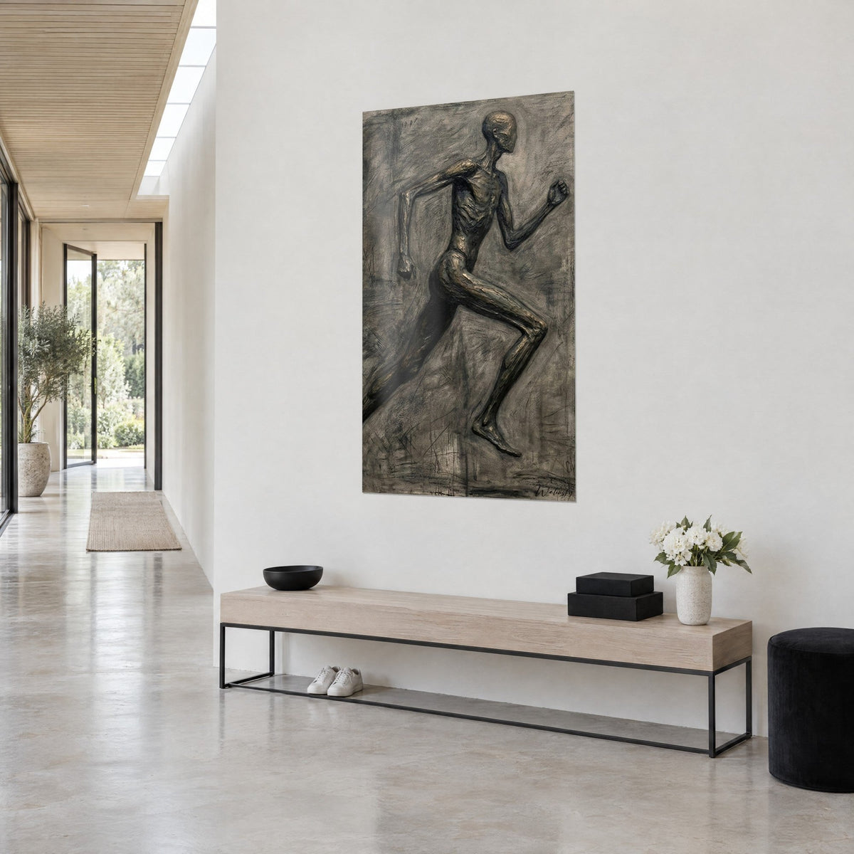 Wall art sculpted sprinter with elongated limbs, bronze patina and streaked charcoal grey background, bent arm, three-quarter view in a light hallway