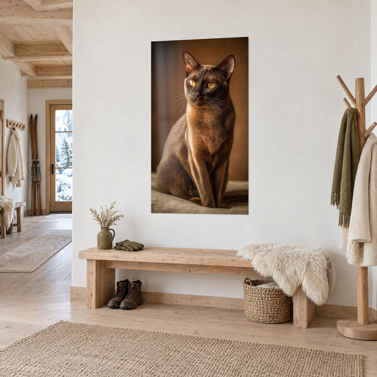 Quadro ritratto felino dal pelo seppia e sguardo dorato, appeso alla parete bianca accanto a una panca di legno in uno chalet