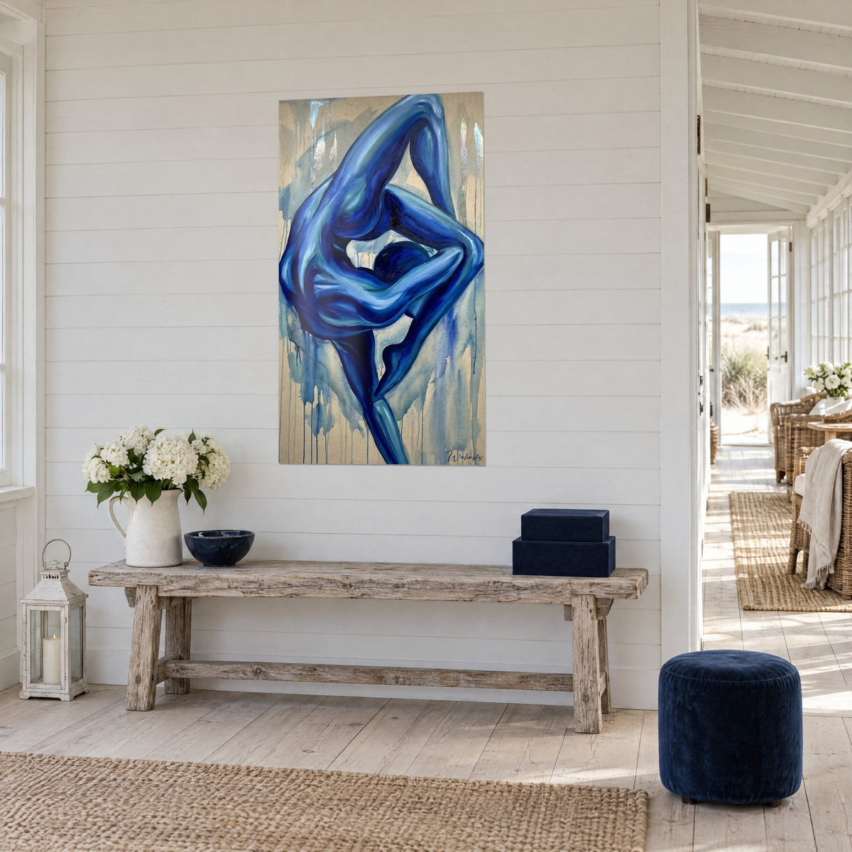 Cuadro acróbata pintada en azul ultramar y turquesa, cuerpo replegado, coladas beige, sobre una pared blanca con paneles de madera, vista de tres cuartos